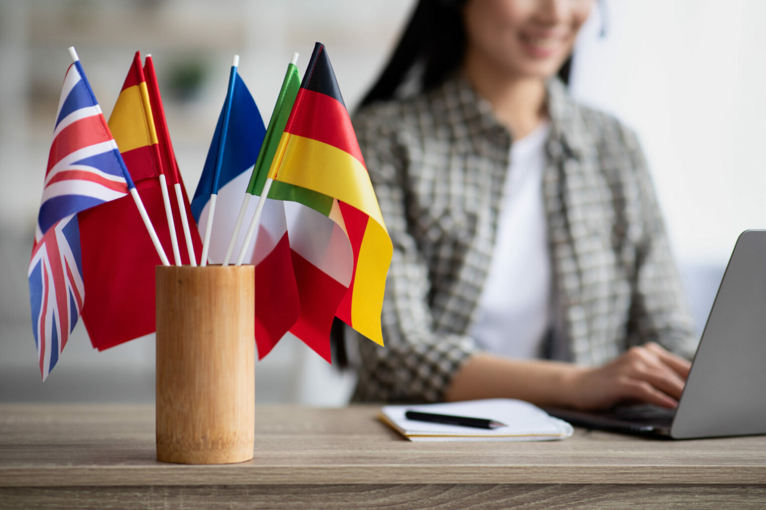 UX Writing: Imagem de uma mulher trabalhando com UX Writing com bandeiras de diferentes países ao lado em sua mesa.