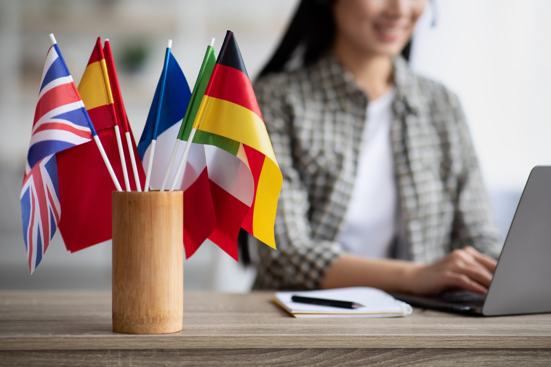 UX Writing: Imagem de uma mulher trabalhando com UX Writing com bandeiras de diferentes países ao lado em sua mesa.